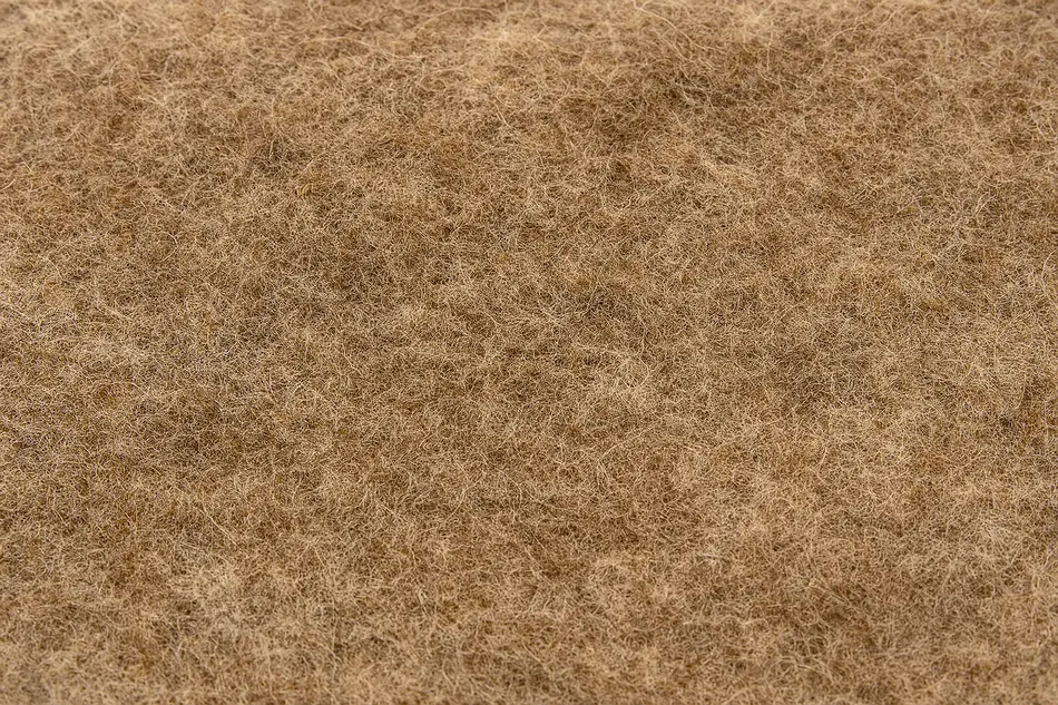 Gros plan sur une feutrine de laine naturelle aux fibres entremêlées, montrant une texture épaisse et irrégulière dans des tons bruns et beiges. Entretien feutrine laine.