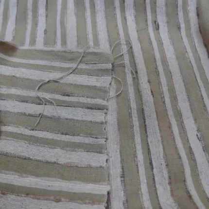 Tissu en lin rayé beige et blanc, couture centrale avec fils lâches – texture naturelle et détails du tissage visibles