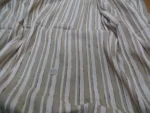 Tissu en lin rayé beige et blanc, couture centrale avec fils lâches – texture naturelle et détails du tissage visibles