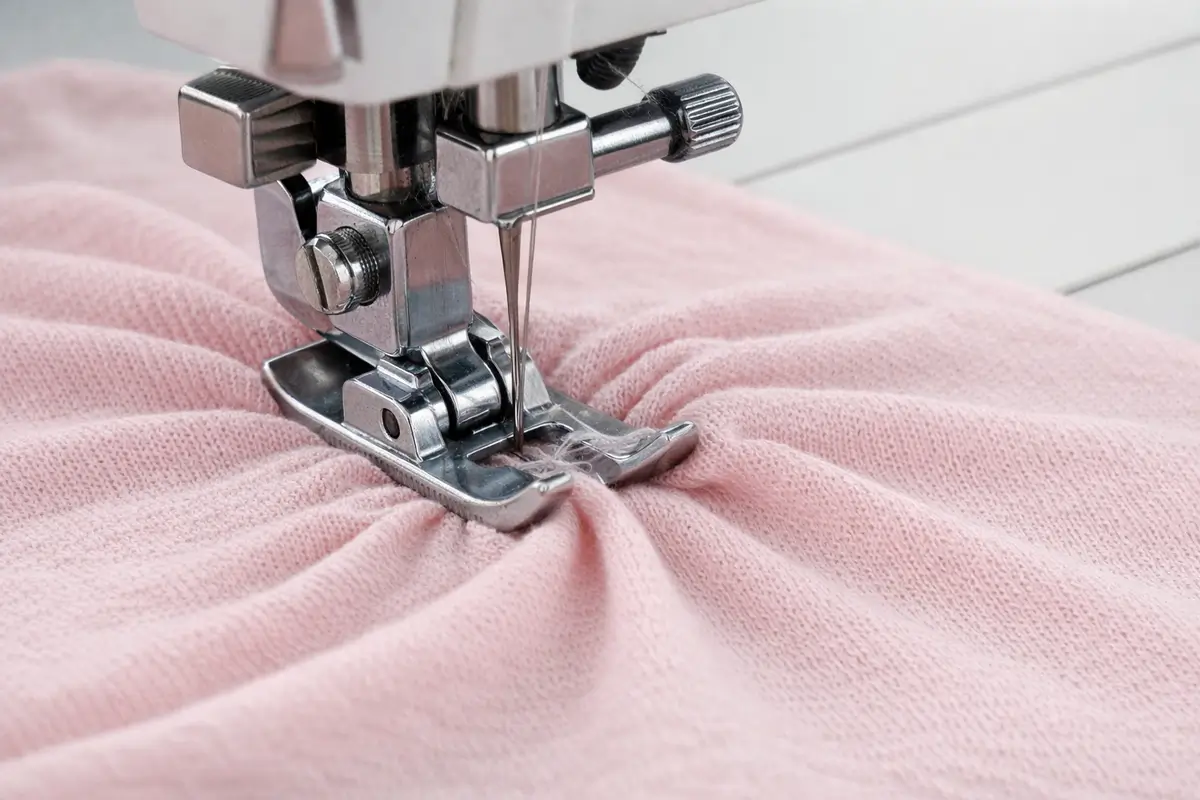 Pied presseur écrasant un jersey fin et provoquant une déformation visible pendant la couture